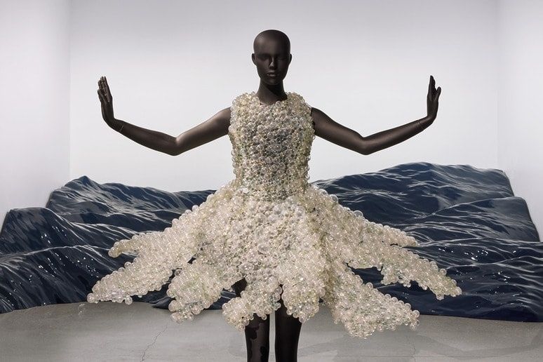 Mannequin in sculpturale jurk van transparante kralen in een museumzaal