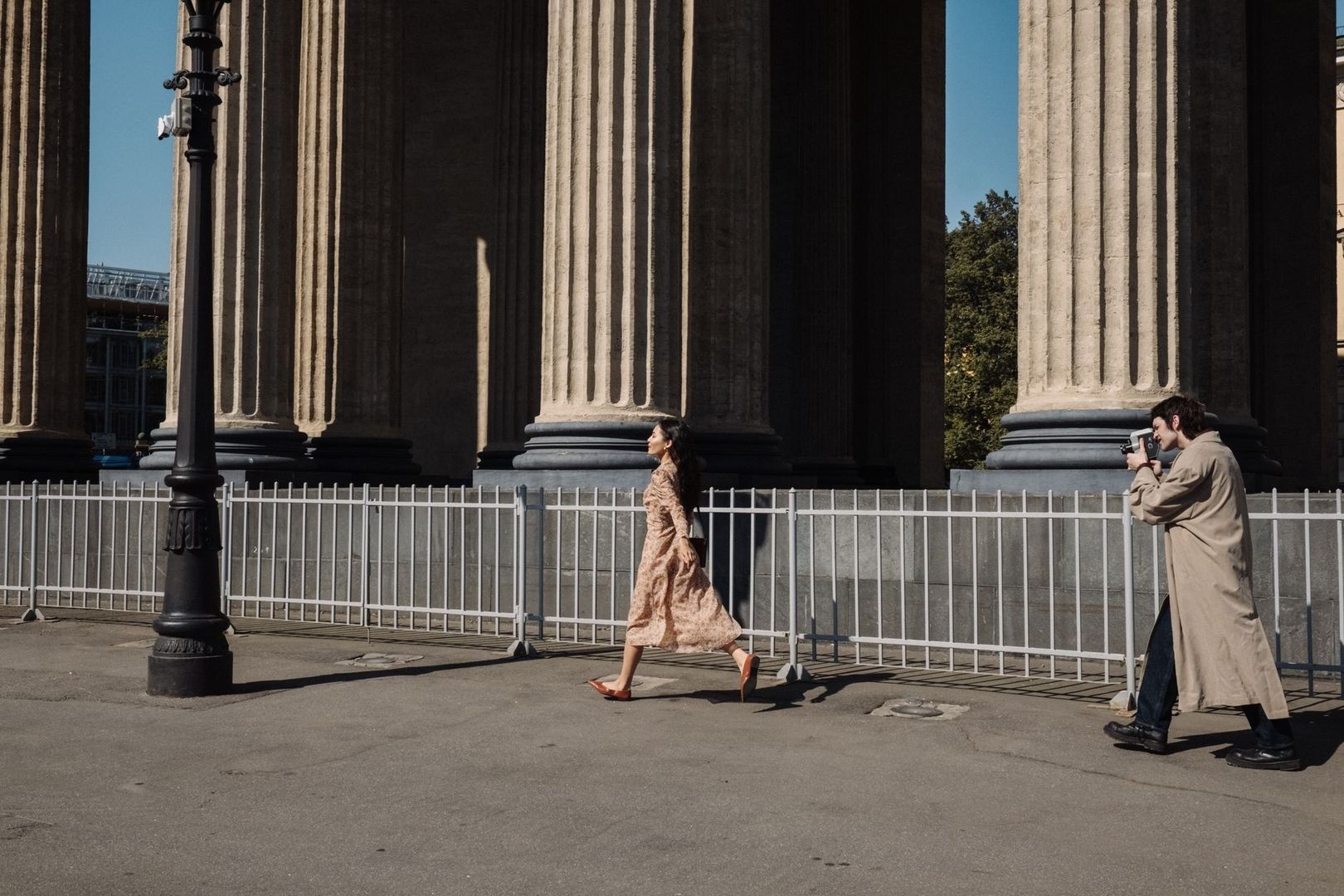 Rauwe modefoto met model en fotograaf tussen monumentale zuilen